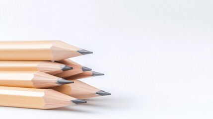 Obraz premium close-up of sharpened pencils neatly arranged and stacked on plain white desk with ample copy space surrounding them