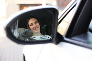 Driver driving modern auto, view through car side mirror