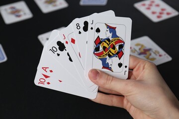 Woman with playing cards at black table, closeup