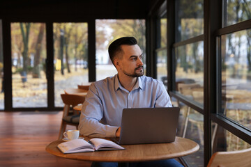 Man working on laptop at table in cafe
