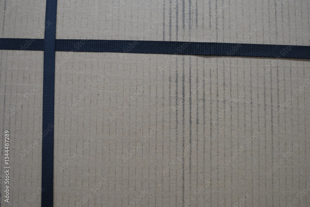 Poster a cardboard box with a black tape running across it. the box is brown and has a cross pattern on it