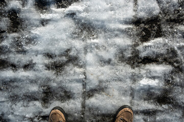 A person's feet are shown in the snow, with the snow covering the ground