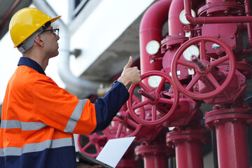 Male engineer inspects water pipelines in the engineering system area of the factory outside where...