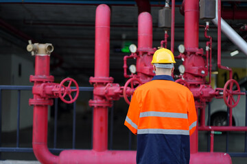 Male engineer inspects water pipelines in the engineering system area of the factory outside where various pipelines are designed modernly. Technicians work in the industry.
