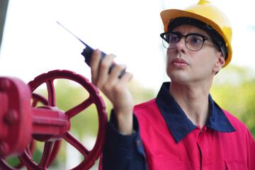 Male engineer inspects water pipelines in the engineering system area of the factory outside where various pipelines are designed modernly. Technicians work in the industry.