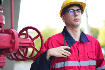 Male engineer inspects water pipelines in the engineering system area of the factory outside where various pipelines are designed modernly. Technicians work in the industry.