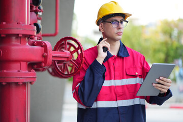 Male engineer inspects water pipelines in the engineering system area of the factory outside where various pipelines are designed modernly. Technicians work in the industry.