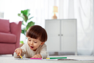 Cute little boy drawing on floor at home, space for text