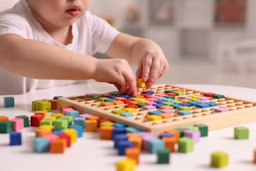 Fototapeta premium Motor skills development. Little boy playing with Times table tray indoors, closeup