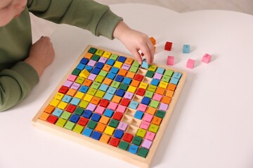 Fototapeta premium Motor skills development. Little boy playing with Times table tray indoors, closeup