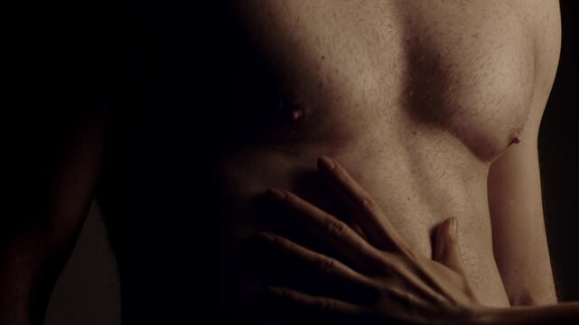 Female hand touching male muscular torso. Slow motion