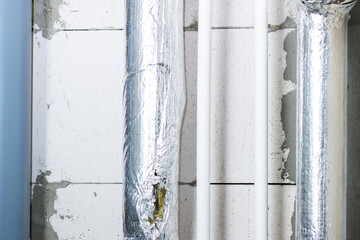 A long row of pipes is neatly wrapped in shiny aluminum foil
