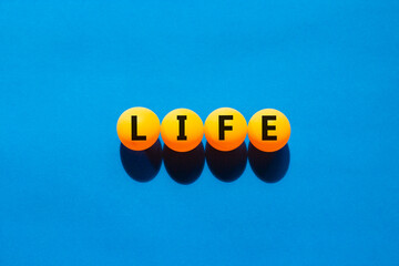 Life symbol. Concept word Life on beautiful yellow ping pong balls. Beautiful blue table blue...