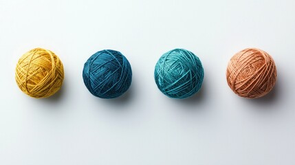 Four balls of yarn in yellow, teal, blue-green, and terracotta arranged in a row on a white background.