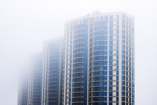 A Misty Urban Landscape Featuring HighRise Buildings Amidst Foggy Atmosphere and Blurry Backgrounds - Powered by Adobe