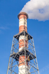 steam rising from a chimney in a thermal power plant. tall chimney above the city.