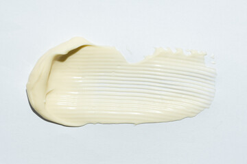 Close-up smear of mayonnaise sauce on white background, top view.