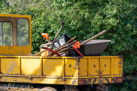 a small delivery van packed with gardening tools. a melex with a wheelbarrow, rakes, shovels, forks and other tools prepared for work.