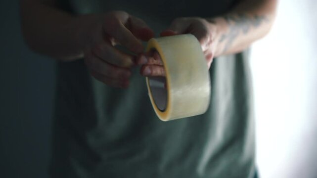A man searches for the edge of a round roll of tape.
A roll of tape in a man's hands.
An office worker can't find where the tape is peeling off