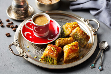 Turkish coffee with baklava sweets on a silver tray. Grey background. Close up.