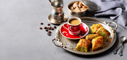 Turkish coffee with baklava sweets on a silver tray. Grey background. Copy space. Close up.