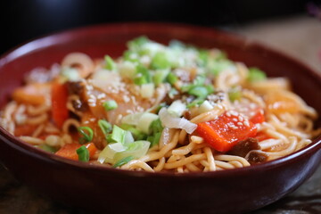 A bowl of noodles filled with meat and vegetables, ready to eat.