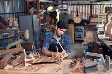 Luthier making top of guitar using traditional tools in workroom with manual tools