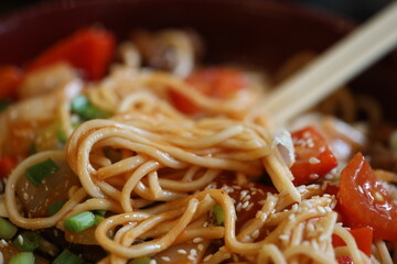 A bowl of noodles and vegetables served with chopsticks, perfect for a quick meal or office lunch.