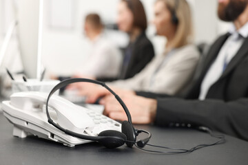 Technical support call center. Team of operators working at table in office, focus on phone and...