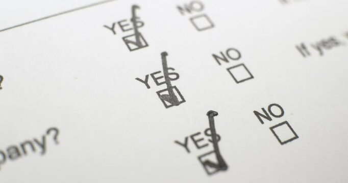 Close up of a paper form with checkboxes for questionnaire, survey, or application with empty Yes or No check boxes for each question. Writing answers to Yes or No with checks or x marks in black ink.