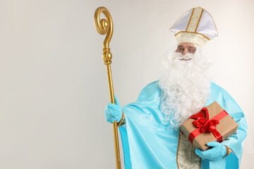 Saint Nicholas with Christmas gift and crozier on gray background, space for text