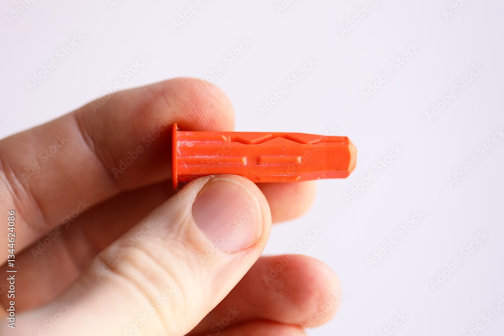 Poster a person holds a small red object in their hand.