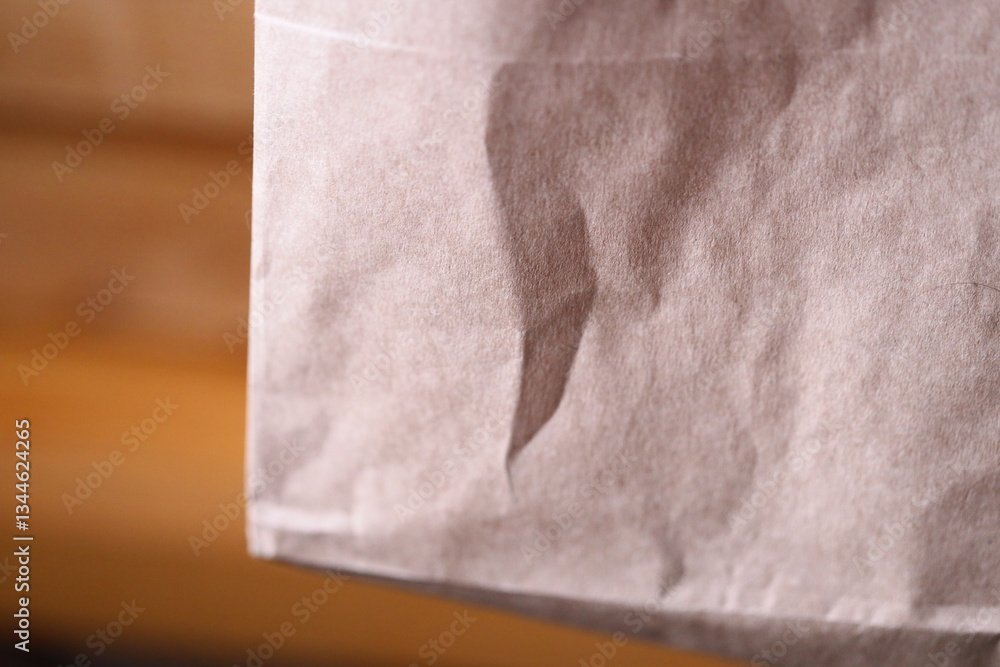 Poster close-up shot of a paper bag on a table, highlighting its texture and design.