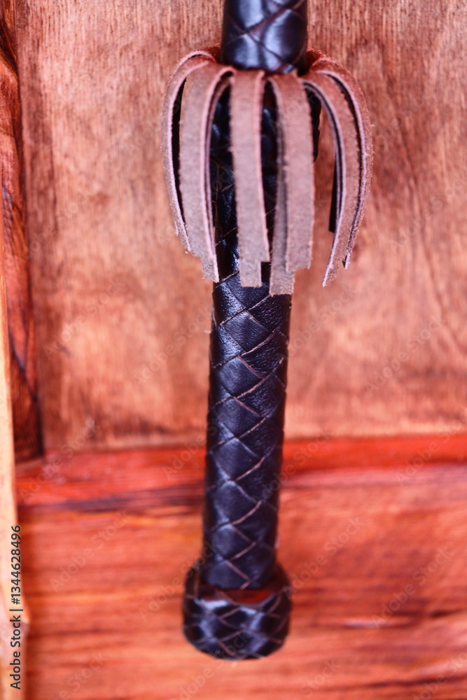 Poster a close-up shot of a leather handle on a wooden door, suitable for use in interior design or archite