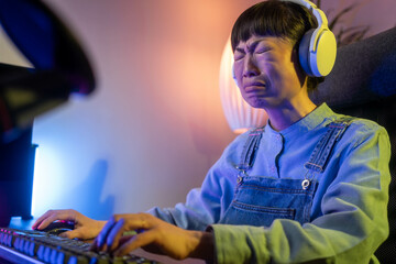 Asian gamer woman addict puzzled influencer streaming play videogame blog computer screen crying confused female blogger shock scam losing game cheat e-sport problem at home © Nenad