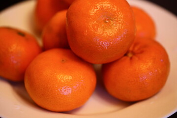 A simple still life composition featuring a white plate topped with oranges on a table.