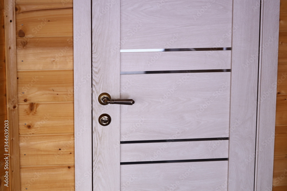 Poster A close-up view of a door handle on a wooden door, suitable for use in interior design or architecture contexts.