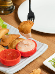 Dipping fried dumpling stick in sauce 