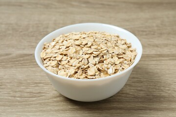 Composition with oatmeal flakes on wooden background. Cooking breakfast