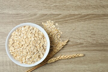 Composition with oatmeal flakes on wooden background. Cooking breakfast
