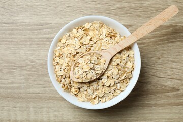 Composition with oatmeal flakes on wooden background. Cooking breakfast