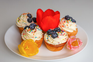 Cupcakes and tulips on a white plate. Confectionary products. Food and drinks. Sweet pastries.
