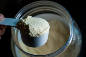 Full scoop of protein powder close-up on a jar background. Sports nutrition for athletes, additional source of protein