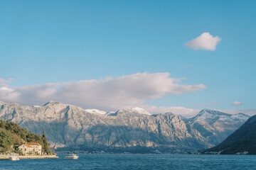 Obraz premium Motor boats moored off the coast with ancient houses at the foot of the mountains