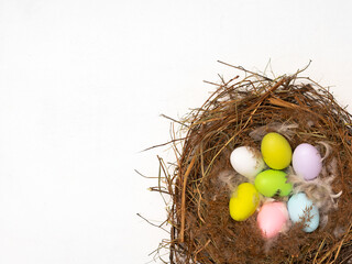 Bird nest, feathers and multicolored eggs on white background, Easter eggs in a nest
