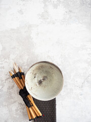Calligraphy brushes and ceramic bowl on textured surface with copy space