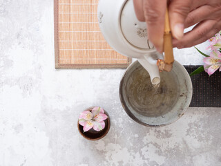 Hands pouring tea into a ceramic bowl during a traditional tea ceremony