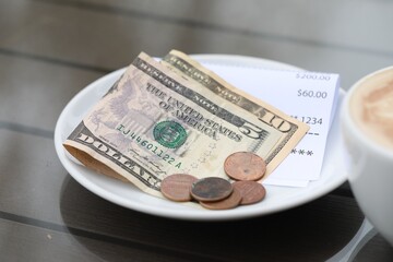 Tip and receipt on wooden table in cafeteria, closeup