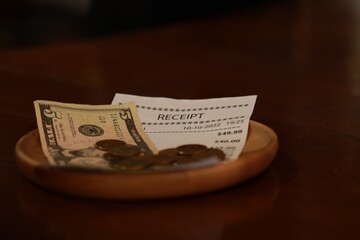 Tip and receipt on wooden table, closeup