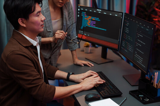 IT developers discussing with point to intelligent website development coder system running data online two screens information technology at neon light room at modern office. Infobahn.